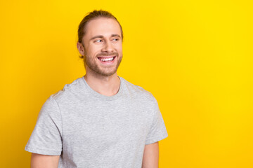Obraz premium Portrait of good mood satisfied guy with long tail hair dressed light t-shirt look empty space isolated on yellow color background
