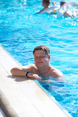 An adult man of 40-44 years old is swimming in a pool with clear water.