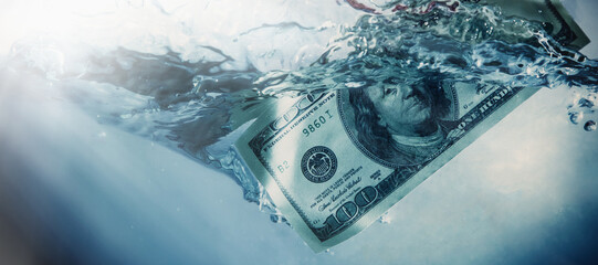 Global financiall crisis concept. Dramatic image of US Dollar sinking in water. Horizontal image.