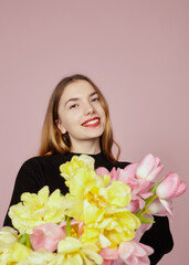 happy woman with a bouquet of tulips on a pink background