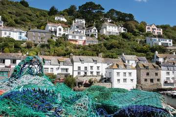 Fishing nets dry in the sun on the harbour wall at the pretty fishing village of Polperro,...