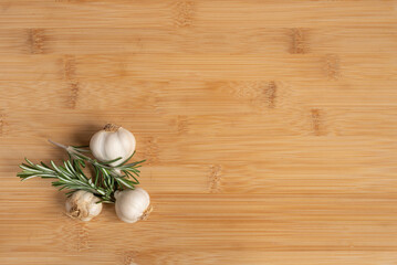 Obraz na płótnie Canvas Garlic and rosemary on kitchen wooden table with copy space .