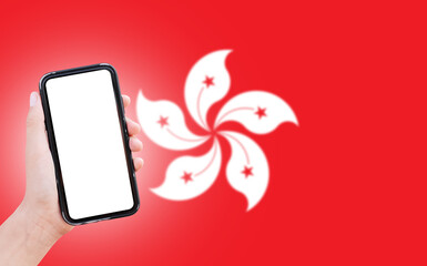 Male hand holding smartphone with blank on screen, on background of blurred flag of Hong Kong. Close-up view.