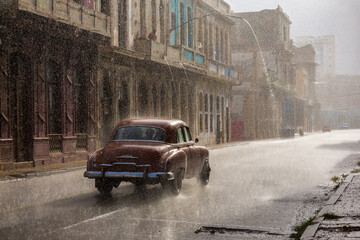Vintage car driving through the rain in Havana.