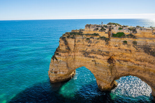 A woman on the top of cliffs at Marinha Beach in Algarve, Portugal