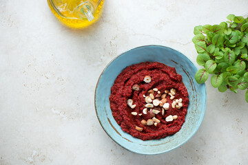 Turquoise bowl with beetroot paste on a light-beige stone background, horizontal shot with copy...