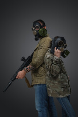 Shot of adult man and young girl in post apocalyptic style with gas masks and guns.