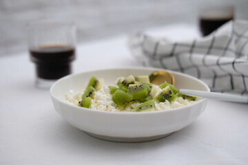 Cottage cheese with fruits and honey in a white plate with a spoon and a napkin, two glasses of coffee on a white background. Healthy breakfast.