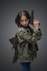 Studio shot of young girl in setting of post apocalypse with backpack and handgun.