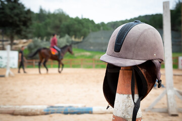 Equestrian equipment. Equestrian helmet in selective focus on dressage area. The rider riding the...