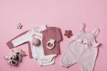 Set of pink clothes and accessories fot newborn girl. Toys, bodysuit, romper, knitted cardigan, shoes, bib on pastel backgroundd. Mock up tor text. Baby shower concept. Flat lay, top view