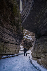 man tourist with beard in sunglasses walking on blue ice in maligne river stone canyon 