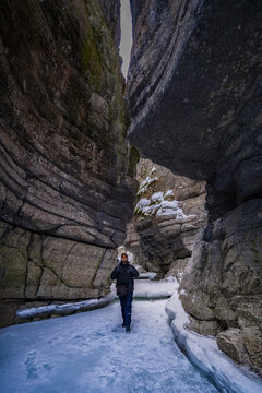 man tourist with beard in sunglasses walking on blue ice in maligne river stone canyon 