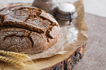 Fresh delicious bread close-up and salt. Freshly baked sourdough bread with a golden crust on a wooden board. The context of a bakery with delicious bread. Confectionery products.