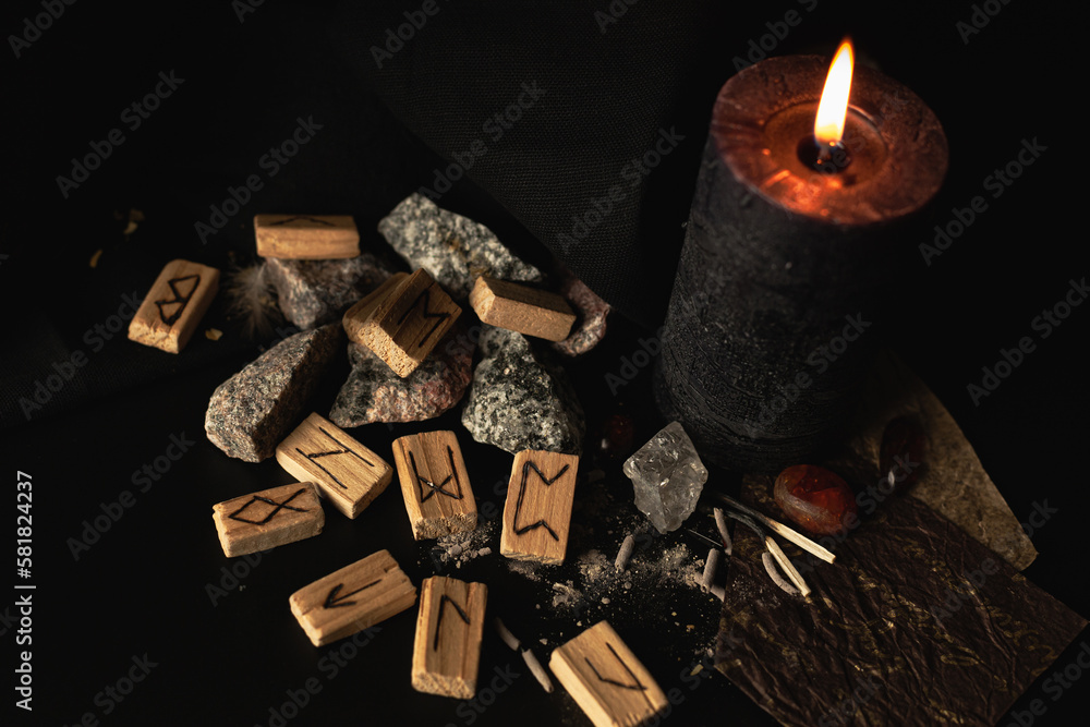 Wall mural wooden runes on a dark background with a candle and amber stones, for a magical ritual