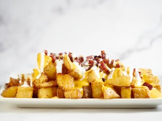 Delicious potatoes with bacon and cheese sauce on a white background