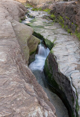 Small river flowing through eroded rock on the beach in Cornwall United Kingdom