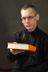 a young man gives an orange book