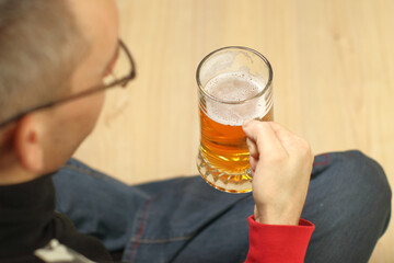 a young man holds a full mug of beer in his handr