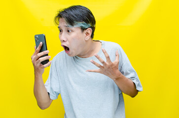 Irritated, depressed, and messed asian young man shouting to phone madly and angrily.