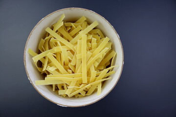 Egg noodles in a round paper package on a gray background. View from above.