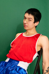 Portrait of tired boxer relaxing and breathing after fight over green background. Concept of sport,...