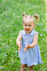 a happy little blonde girl runs in the park in the summer on the green grass. Earth Day. Children Protection Day