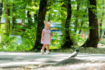 cute little girl in a purple muslin dress walks in the park in the woods in summer.Earth Day. Children Protection Day