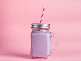 blueberry smoothie in mason jar glass on pink