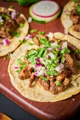 Asada tacos with a variety of fillings, served on a rustic brown wood platter