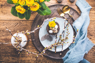 Easter table setting with spring flowers and cutlery on wooden table
