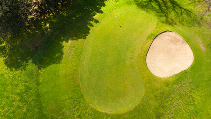 Aerial perpendicular view of an empty golf course with green hills and sand bunkers. The sports club is empty and nobody is playing. Sports concept.