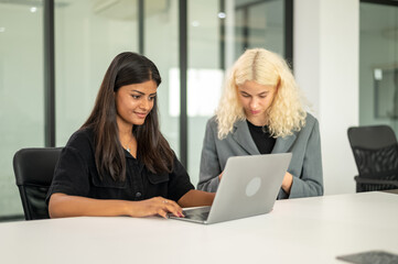 Indian student using laptop in library room  with friend