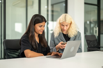 Indian student using laptop in library room  with friend