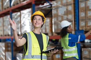Female warehouse worker working at work checks stock, inventory with tablet on shelf pallet in the...