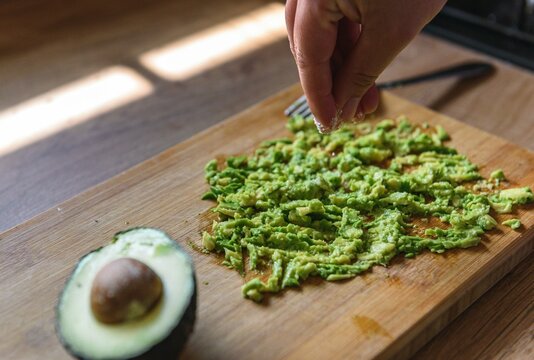 Woman Adding Salt To Avocado