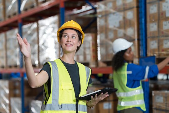 Female warehouse worker working at work checks stock, inventory with tablet on shelf pallet in the storage warehouse. Warehouse worker working with tablet in warehouse