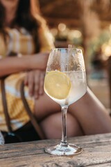 Vertical shot of a  refreshing lemonade in a wine glass on table at a beach bar