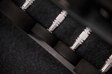 dumbbells on the rack in the gym. Rack with dumbbells in the gym. Metal dumbbells on the rack for athletic and healthy people for training in the fitness room.