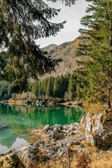 Vertical view of Lake Fusine with shallow water surrounded by lush trees and rocks in Italy