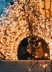 Vertical shallow focus of hang yellow garland lights on the background of an illuminated arch