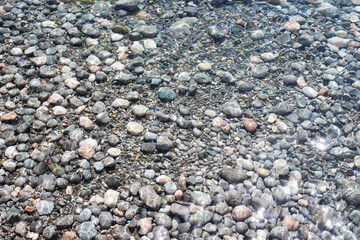 Multicolored pebbles in clear shiny sea water