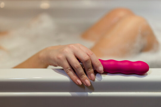 Woman in bath holding vibrator in hand 