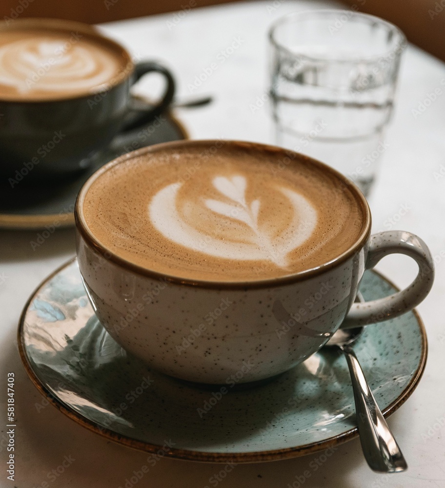 Sticker Closeup of a cup of latte with an art pattern on a table in a cafe