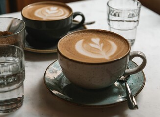 Closeup of two cups of cappuccino with latte art on a table in a cafe