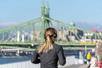 Woman with headphones jogging on the promenade by the Danube river in Budapest, Hungary