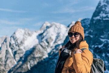 Fototapeta na wymiar Closeup of a happy woman standing in front of mountain peaks in Julian alps in Slovenia