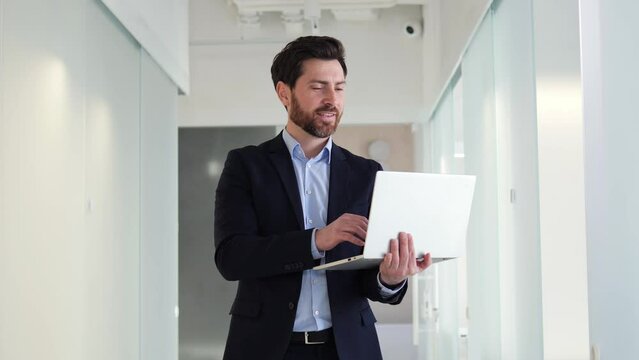 Smiling focused businessman deep in thought, brainstorming ideas and taking notes on his laptop in office. Man determined, ambitious, and driven, always seeking innovative strategies to achieve goals.