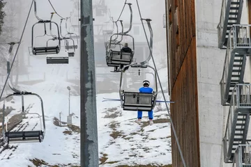 Foto op Aluminium Ski resort with people enjoying rides on ski lifts on a misty winter day © Marko Klarić/Wirestock Creators