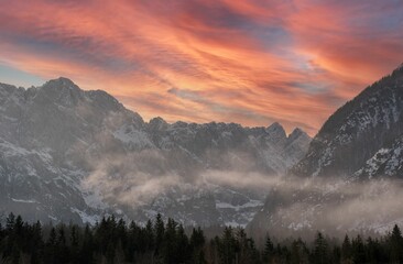 Gorgeous sunset at the Tamar Valley with warm copper clouds above the snowy Julian Alps in Slovenia